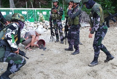 Members of a passing military patrol stop to observe the release of pawikan hatchlings